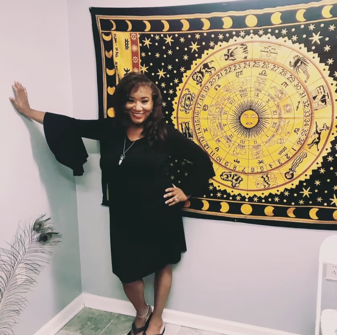 Ericka Boussarhane beside a zodiac wheel tapestry