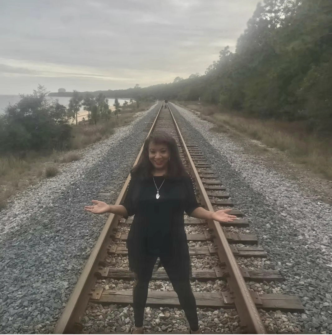 Ericka Boussarhane standing on railroad tracks at dusk
